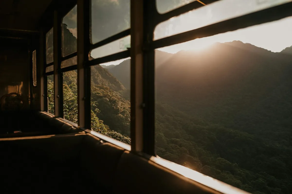 A serene view of mountains from a train during sunset, showcasing nature's beauty.