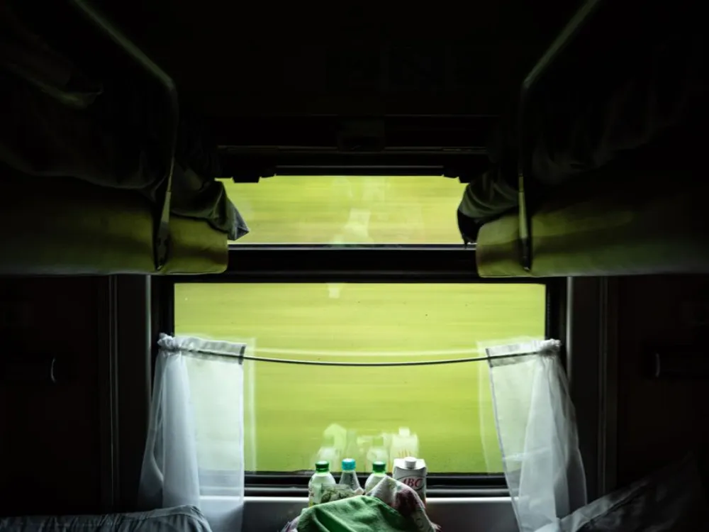 A scenic view from a train compartment window, showcasing greenery and travel-inspired coziness.